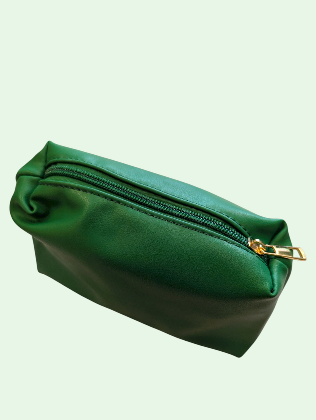 Green makeup bag with a gold zipper on a light green background