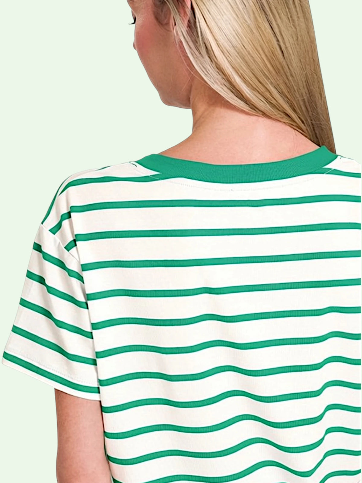 A woman shown from the back wearing a short-sleeve striped T-shirt with green horizontal stripes on an off-white base and a solid green crew neck.