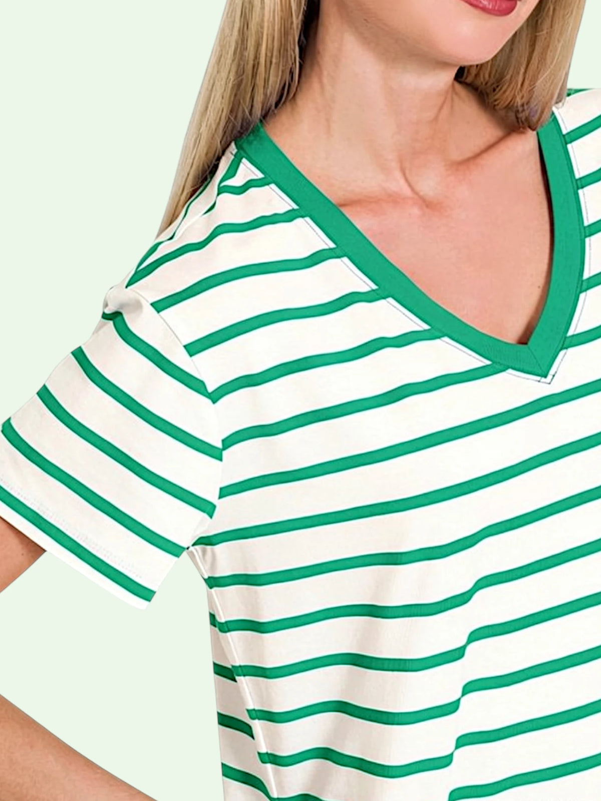 Close-up of a woman wearing a short-sleeve V-neck top with horizontal green and white stripes and a solid green trim.