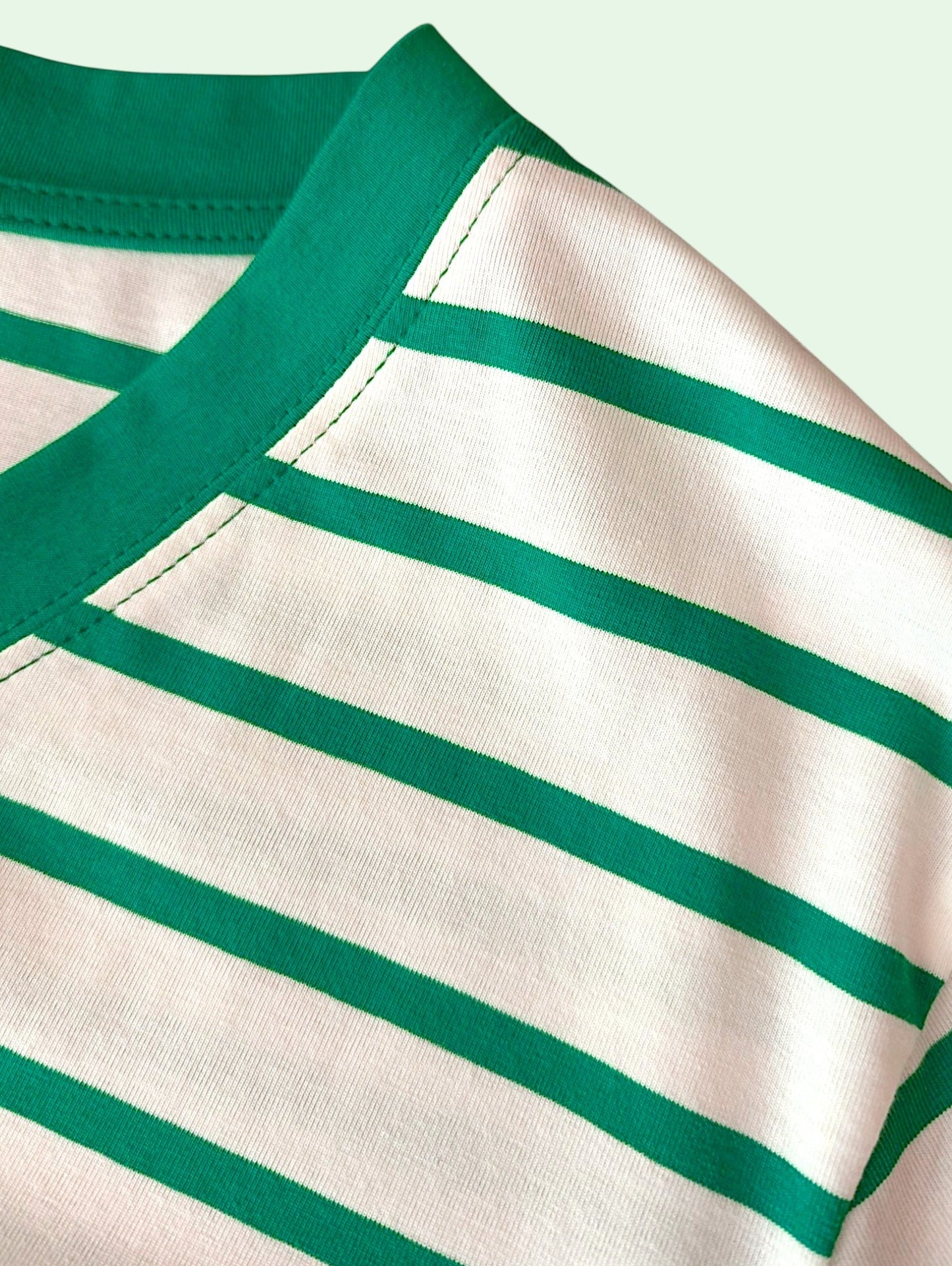 Close-up of a striped knit garment showing a cream base with horizontal green stripes and a solid green collar.