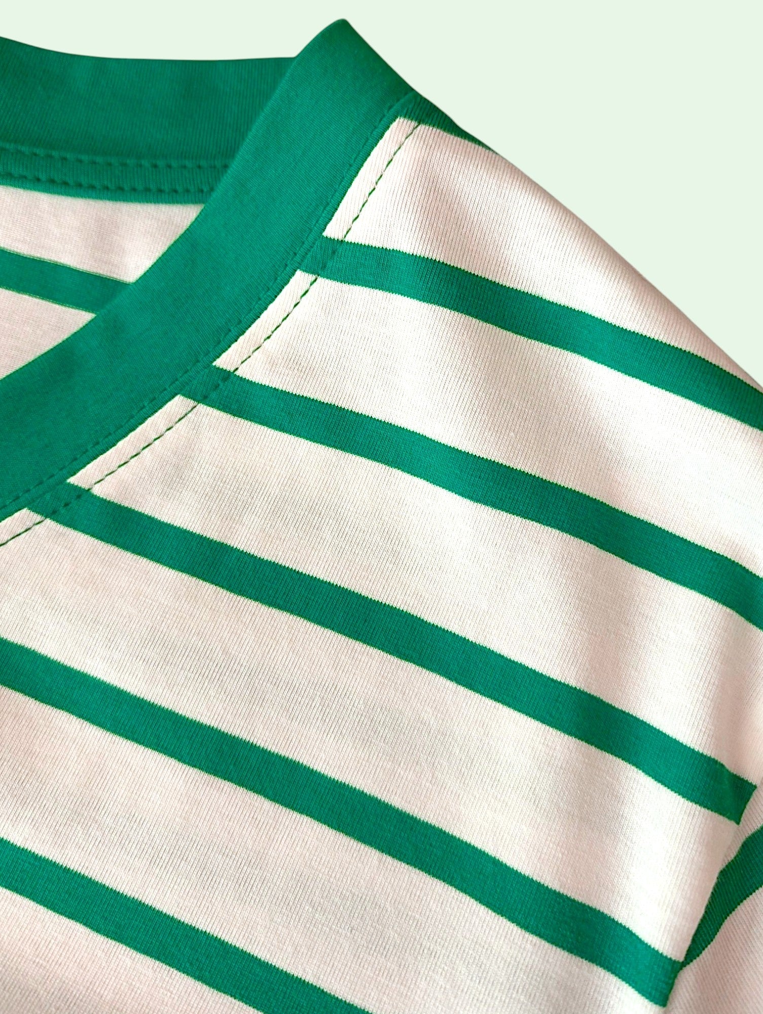 Close-up of a striped knit garment showing a cream base with horizontal green stripes and a solid green collar.