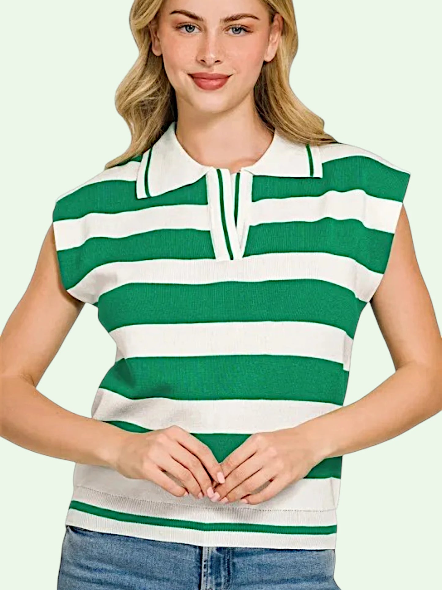 A woman wearing a sleeveless knit polo shirt with bold green and white horizontal stripes, paired with blue jeans, against a solid pale green background.