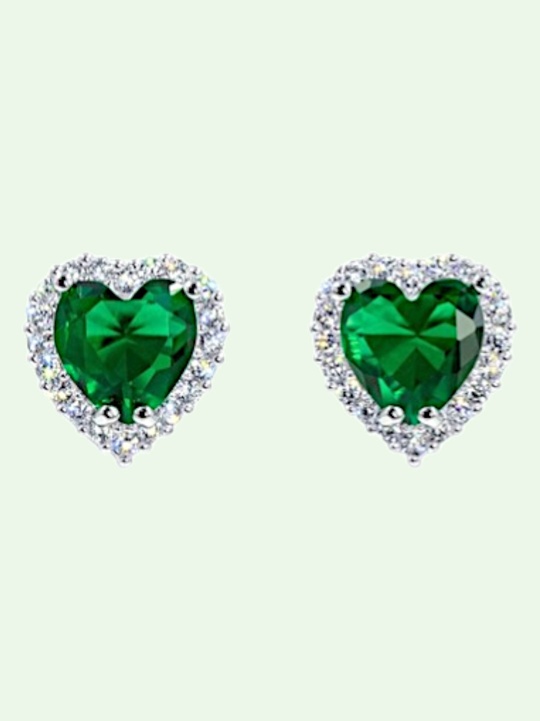 Heart-shaped green gemstone earrings on a light green background