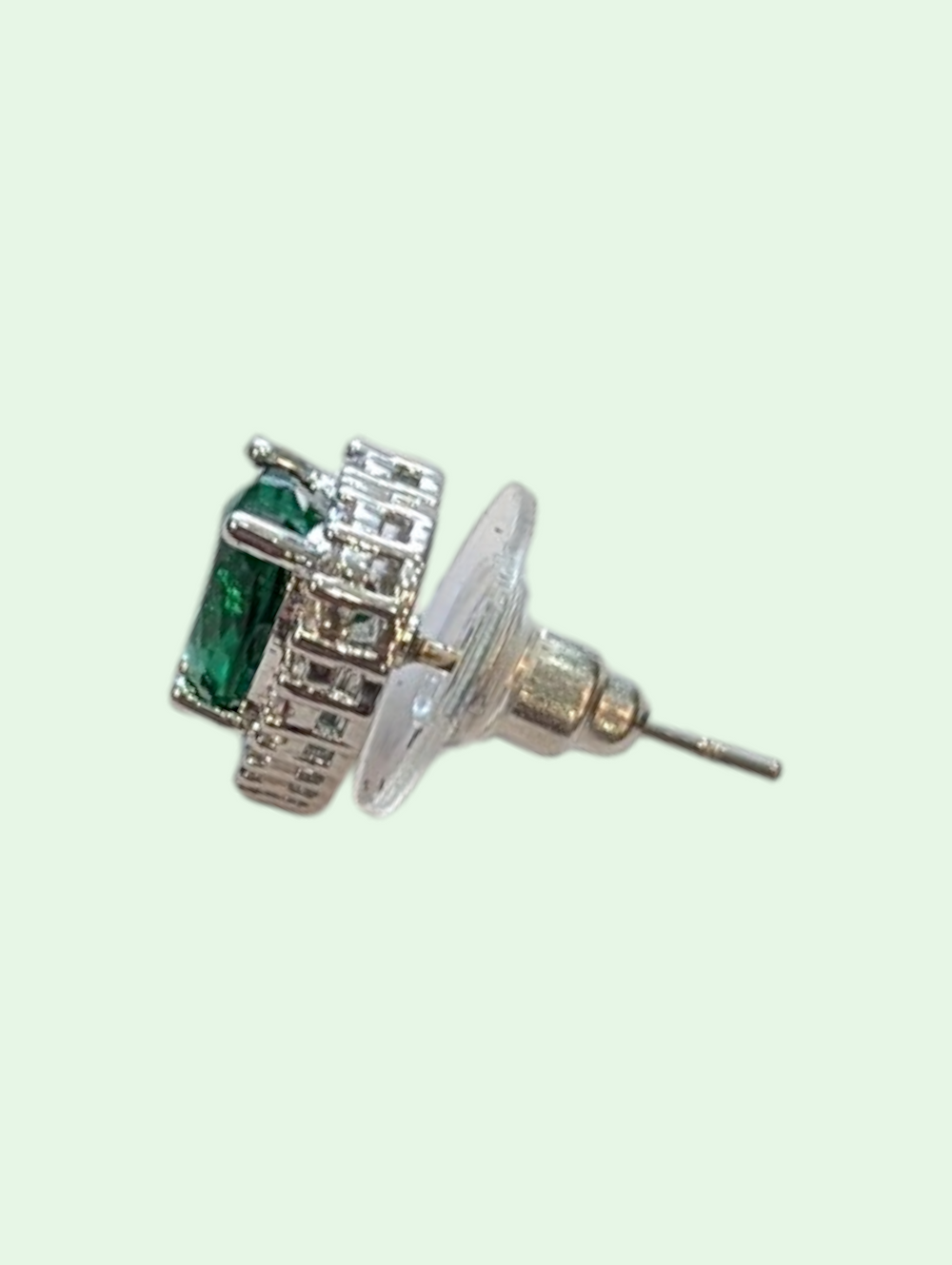 Silver earring with green gemstone on a white background