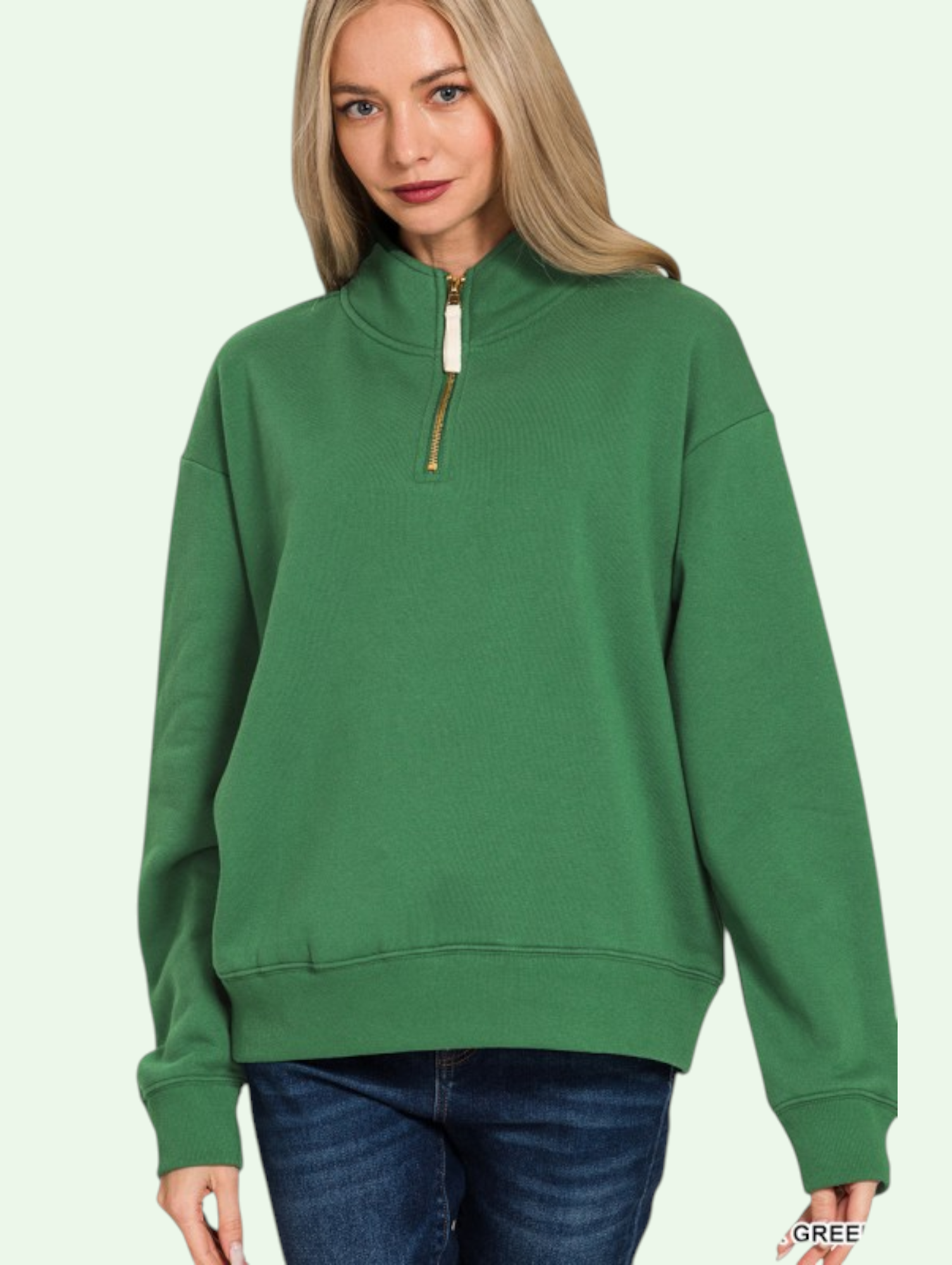 Person wearing a green sweatshirt with a zipper on a light green background