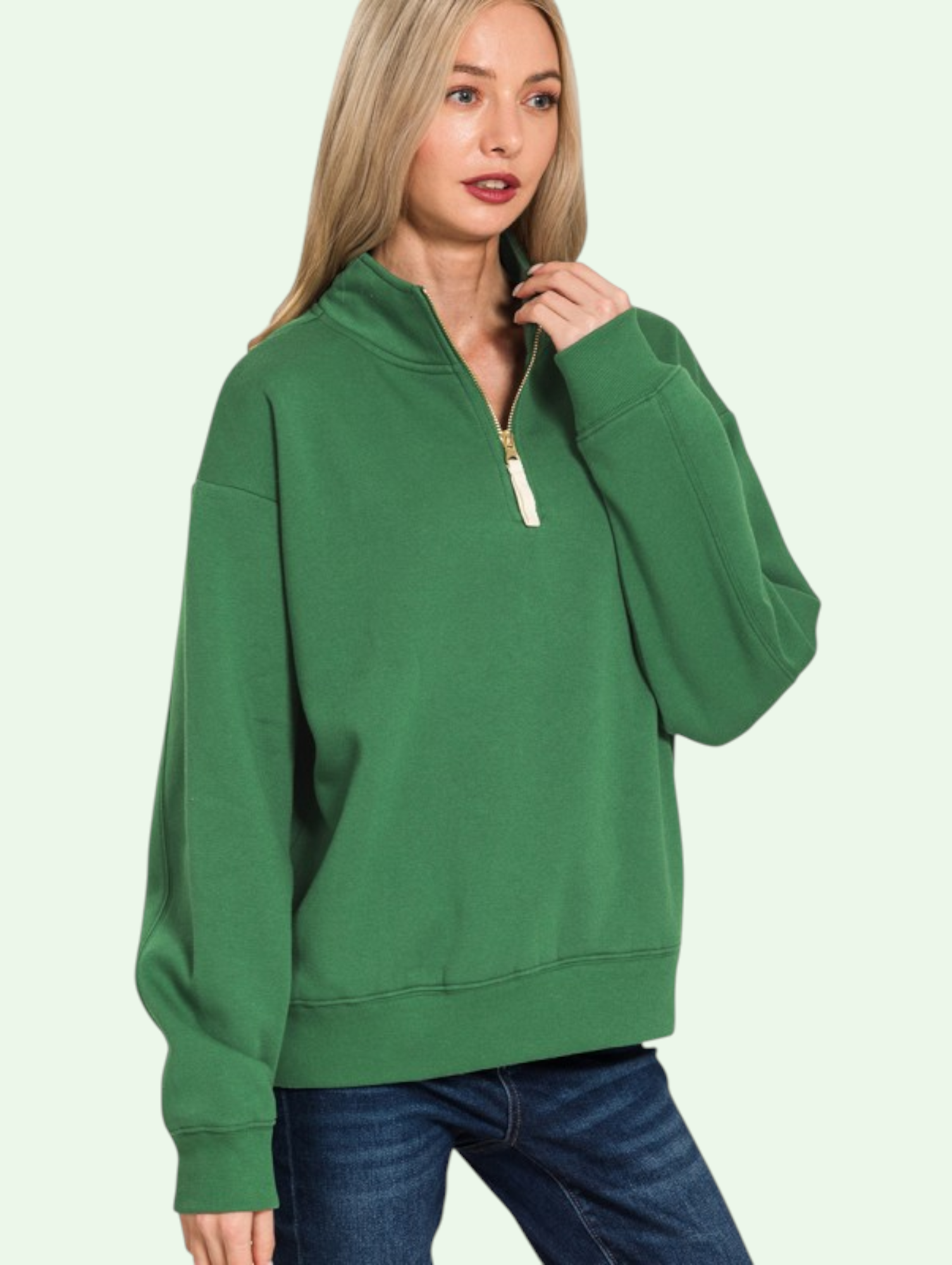 Woman wearing a green sweatshirt with a zipper on a light green background