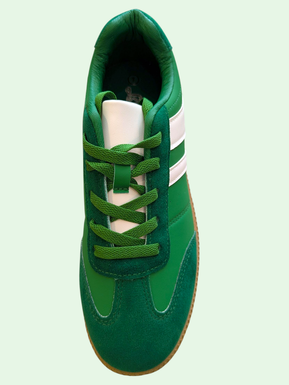 Green sneaker with white stripes on a light green background