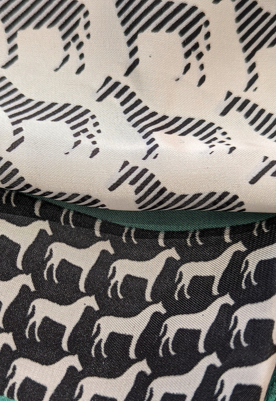 a closer detail of the main repeating horse pattern in a stripe and the border pattern  of horses in a solid white horse outline on black