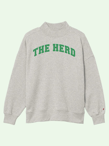 A light heather gray sweatshirt with 'THE HERD' printed in green varsity-style block letters across the chest, displayed on a pale mint green background.