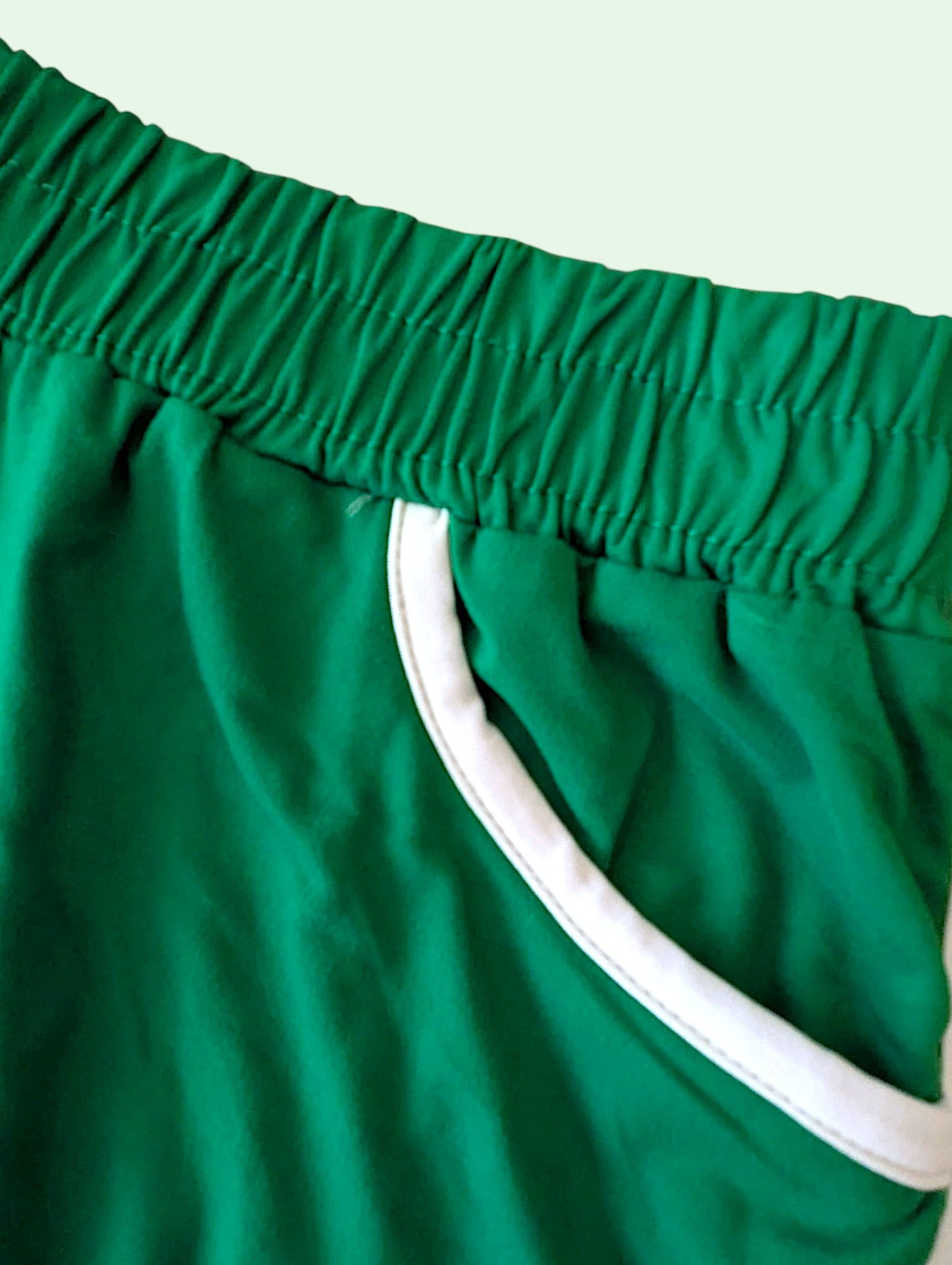 Green shorts with white trim on a light green background