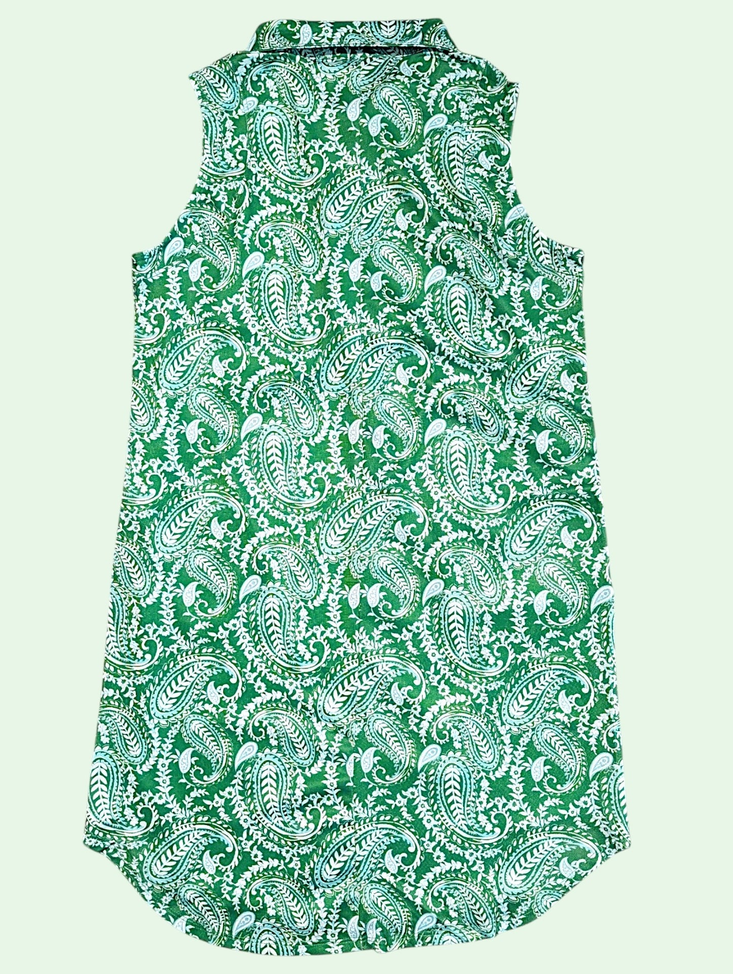 A sleeveless collared shirt dress featuring an all-over green and white paisley pattern, shown against a solid pale green background.