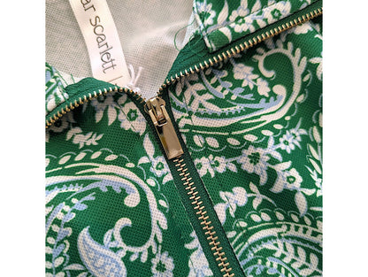 Close-up of a green and white paisley patterned garment with a gold zipper and a visible neck label reading 'scarlett'.