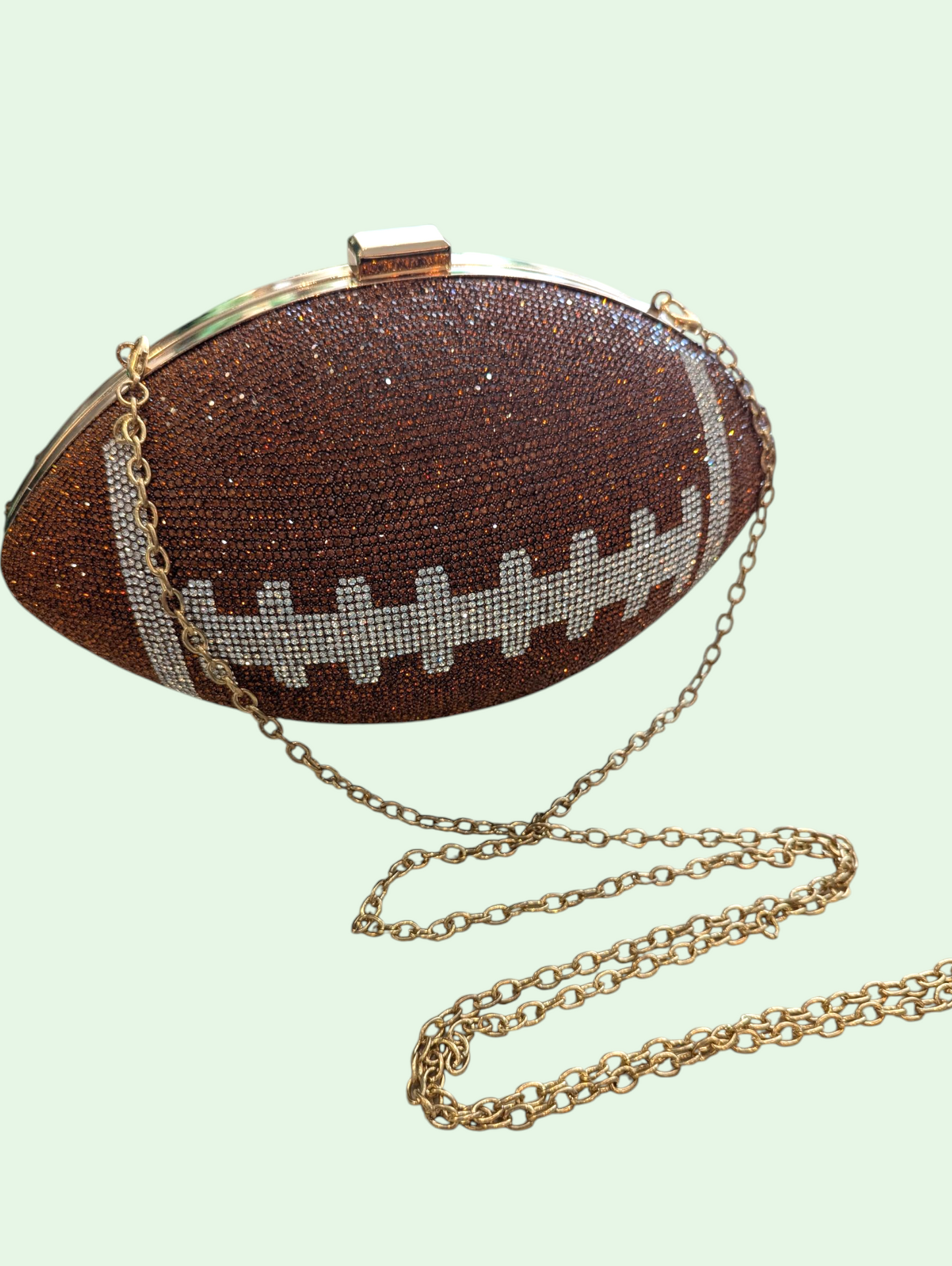 Football-shaped handbag with rhinestone details on a light green background