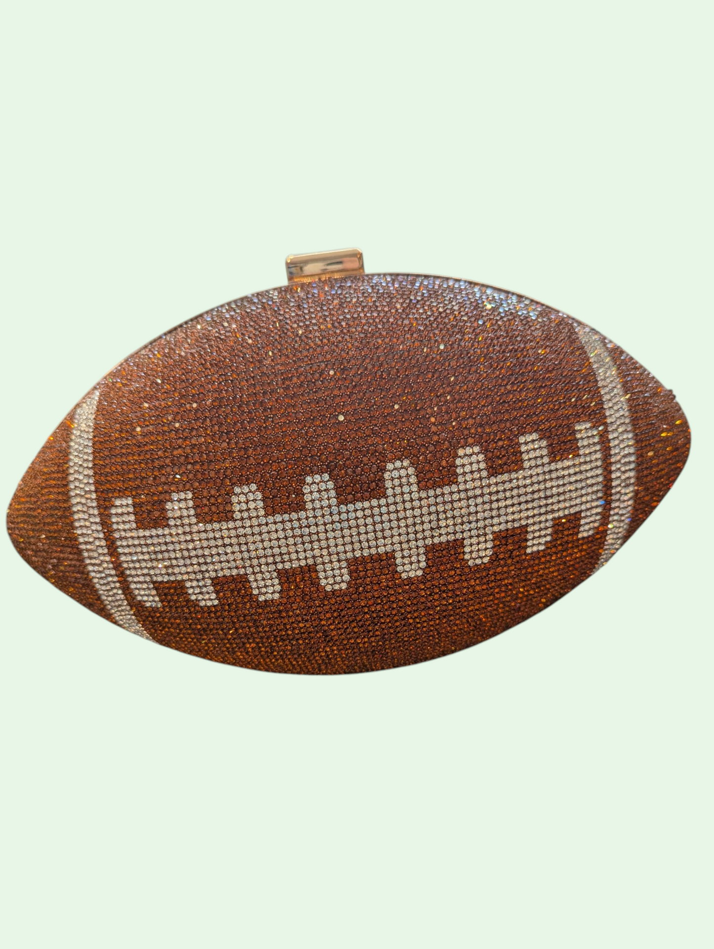 Football-shaped clutch bag with rhinestone details on a light green background
