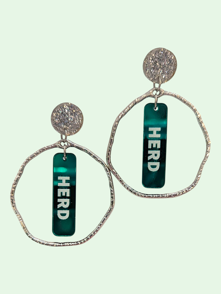 Earrings with 'HERD' text on green bars against a light green background