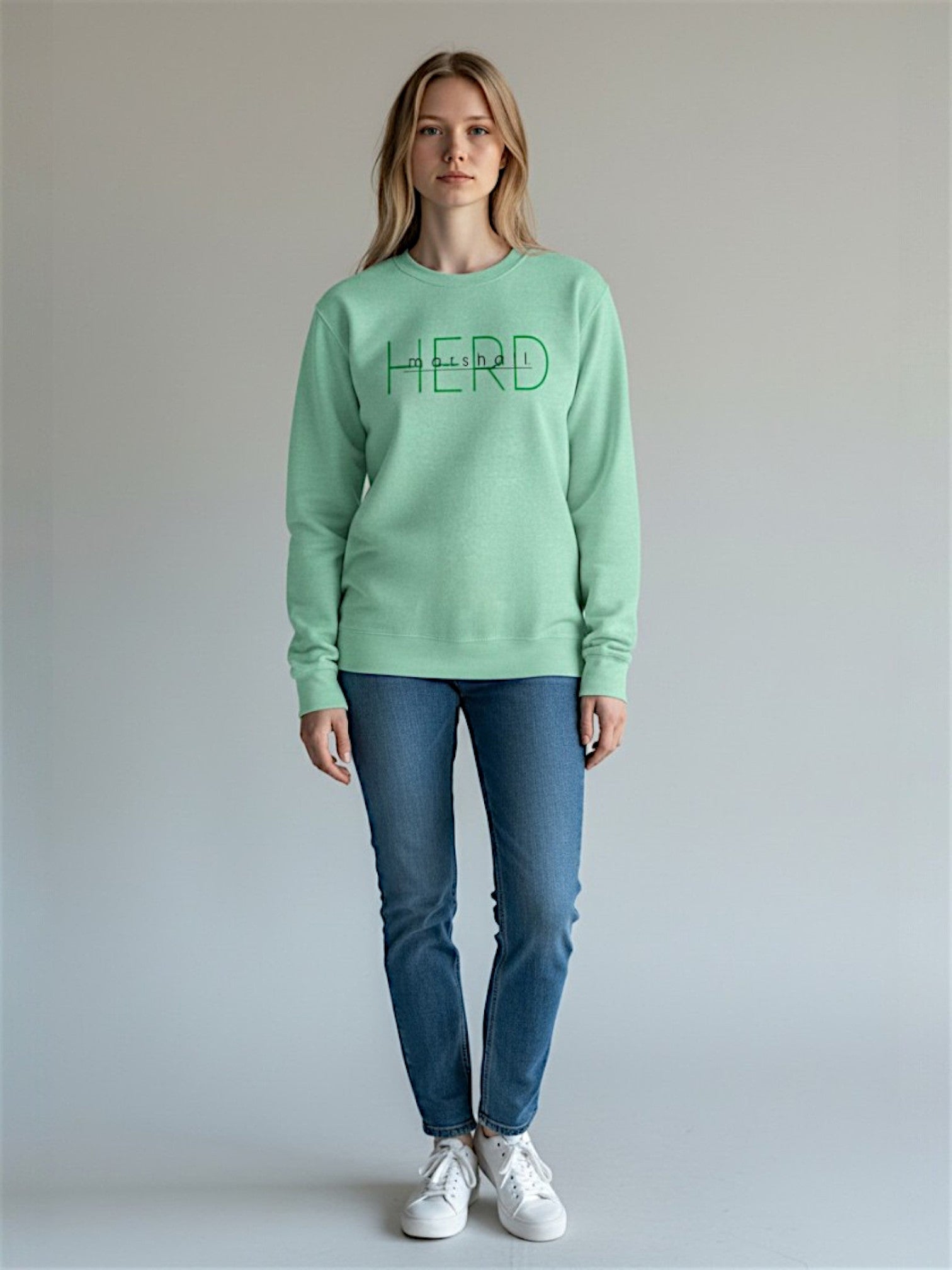 Person wearing a light green sweatshirt with 'HERD' text, standing against a plain background