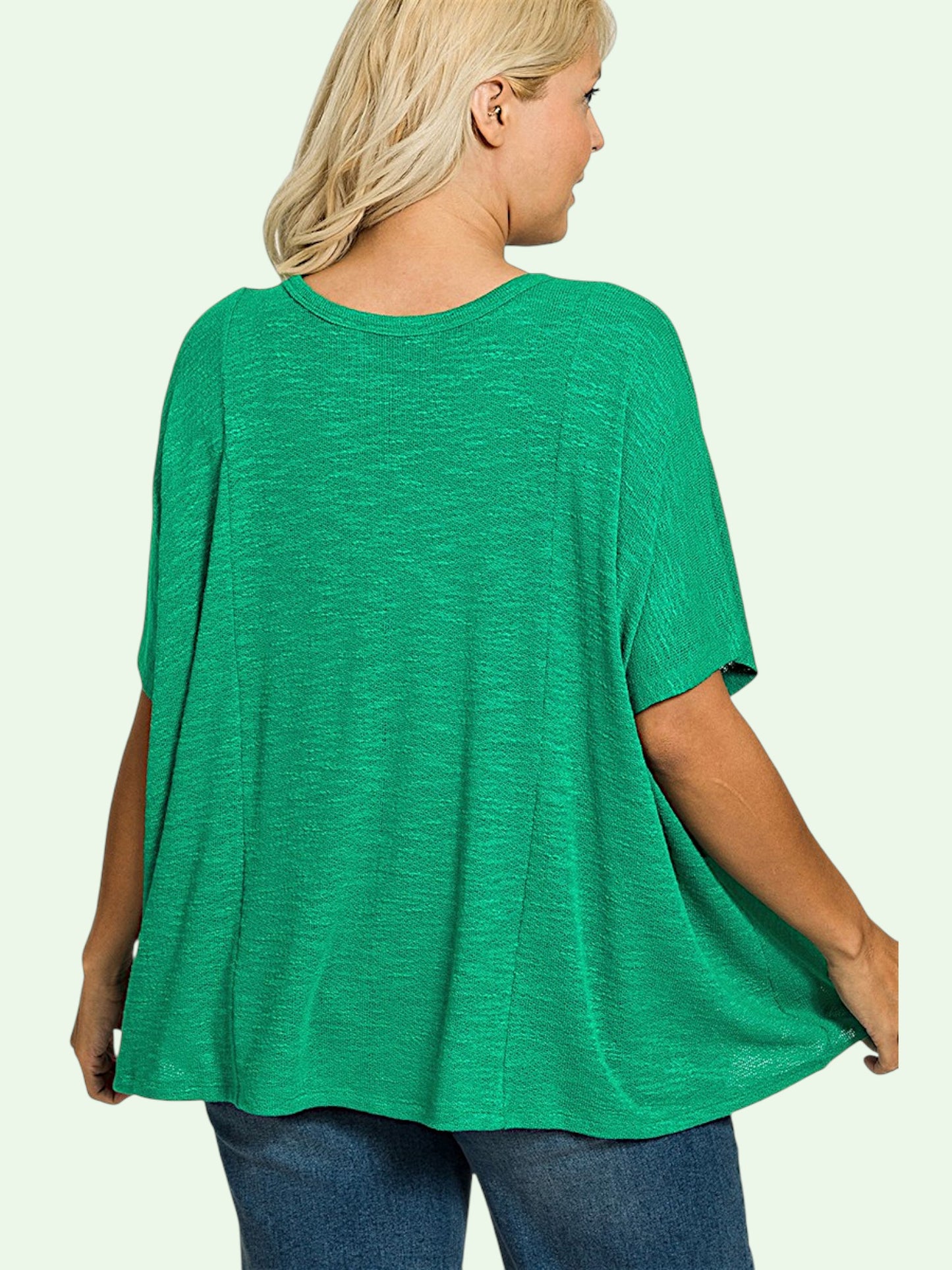 Person wearing a green oversized t-shirt on a plain background