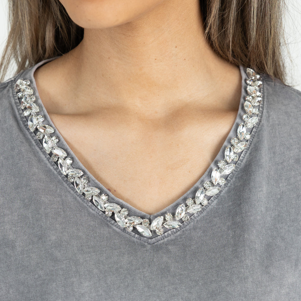 Gray top with crystal embellishments on a plain background