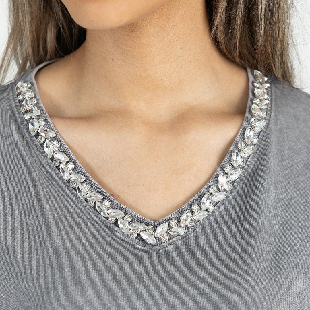 Gray top with crystal embellishments on a plain background