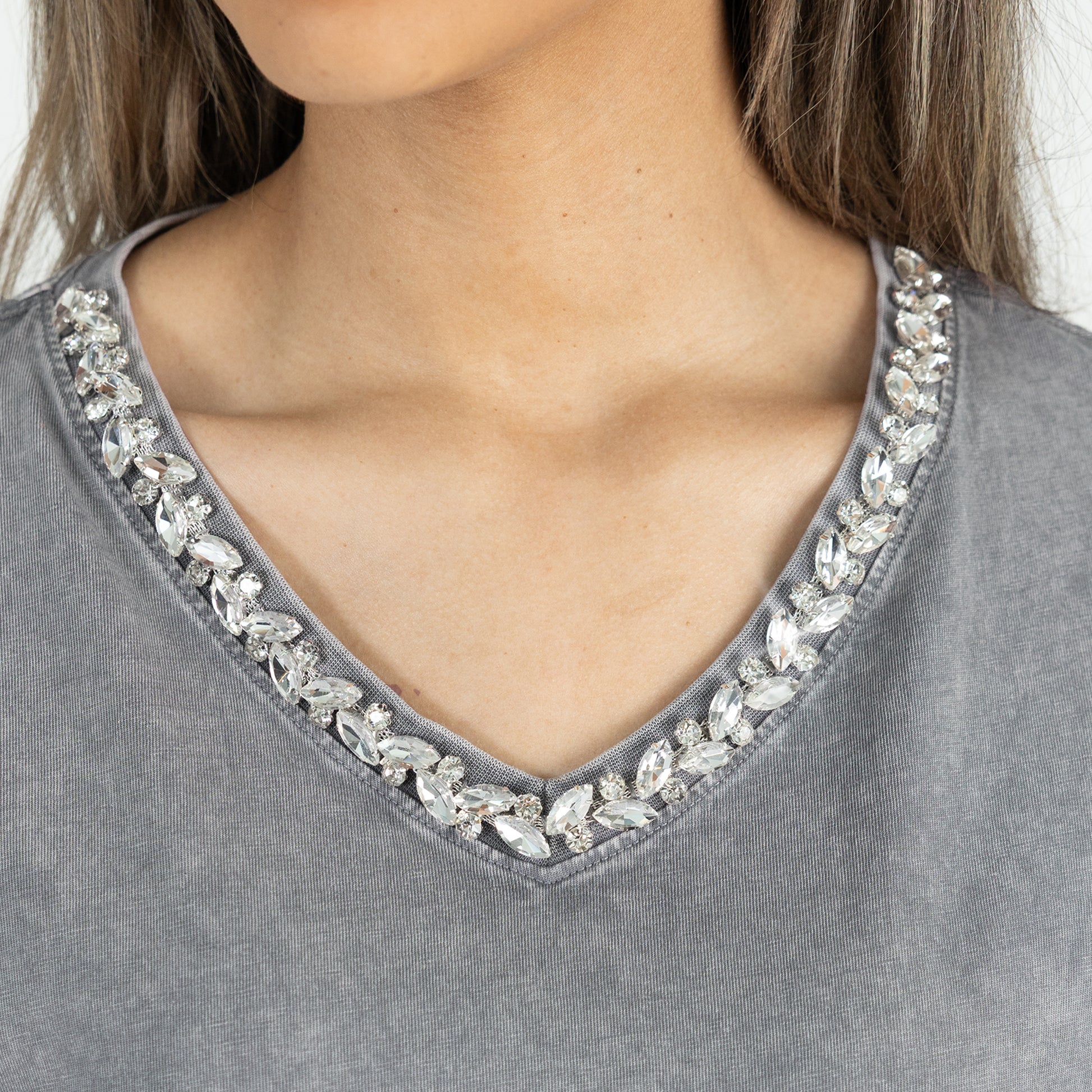 Gray top with crystal embellishments on a plain background
