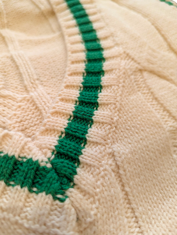 Close-up of a cream knit fabric with green stitching