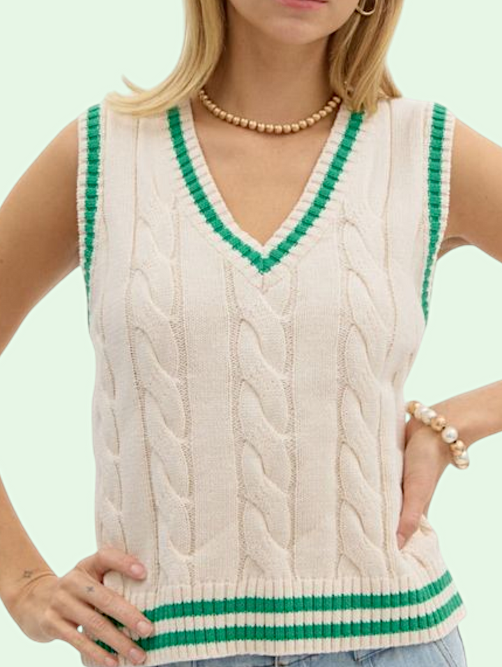 Woman wearing a cream-colored sleeveless knitted sweater with green trim against a light background