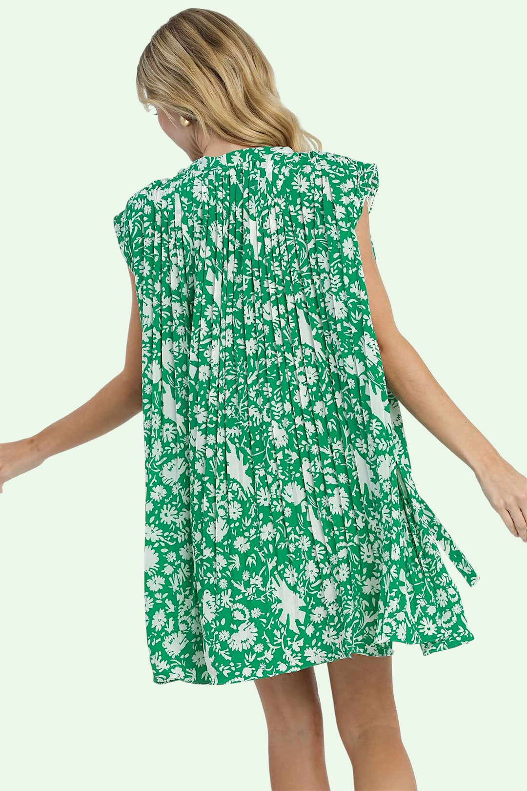Woman wearing a green floral dress on a light green background