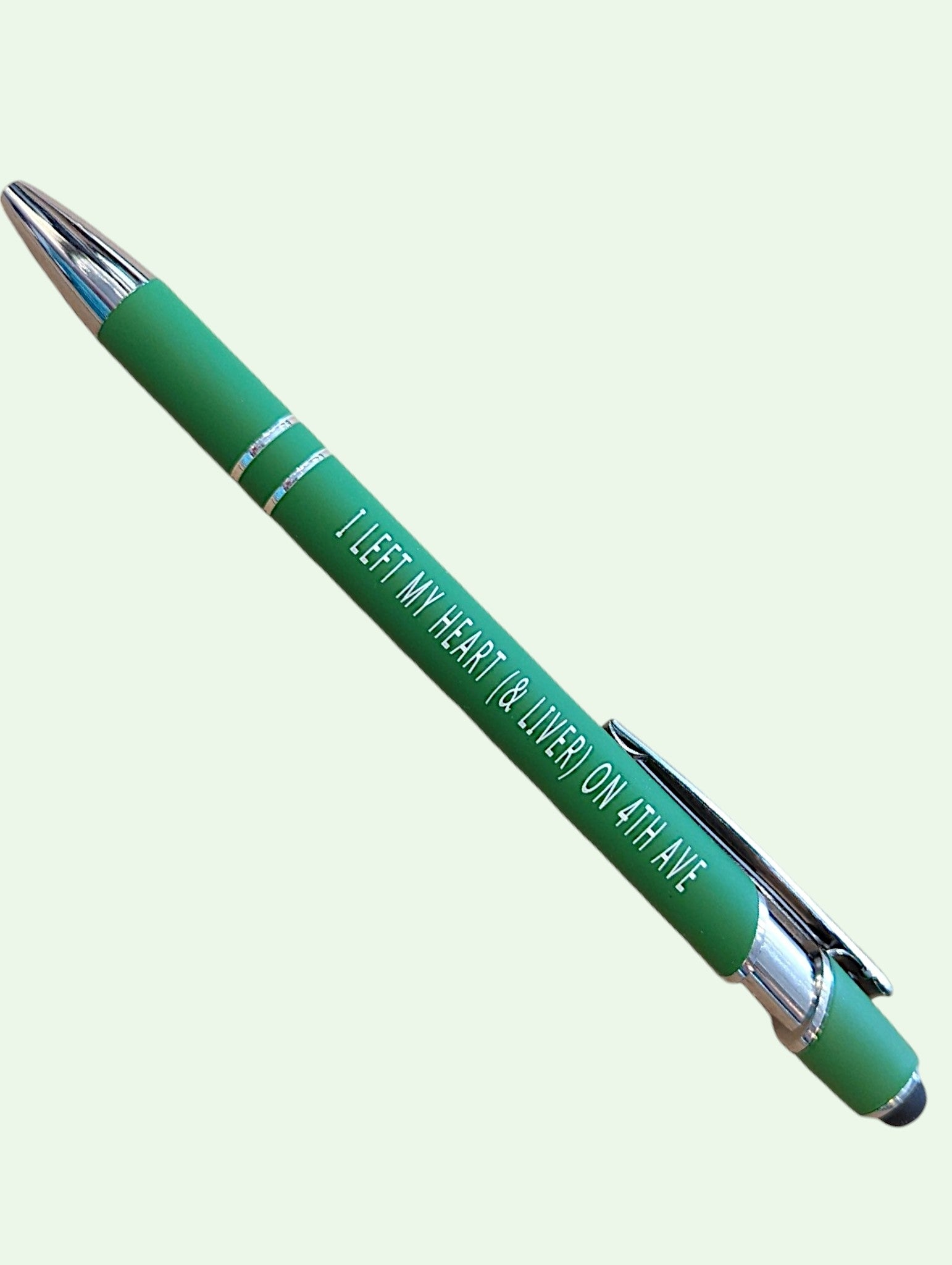 A green ballpoint pen with silver accents and white text that reads 'I LEFT MY HEART & LIVER ON ATLANTA', shown diagonally on a pale green background.