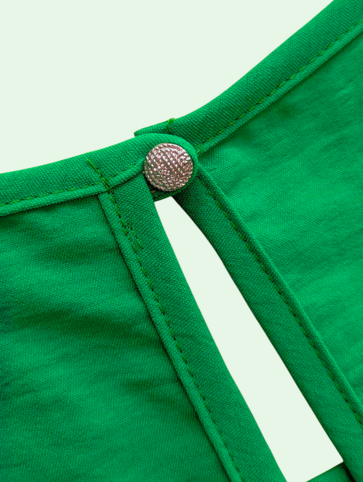 Close-up of a green garment with a button on a light green background