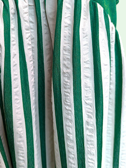 A close-up of a green and white vertically striped fabric with textured, gathered pleats.
