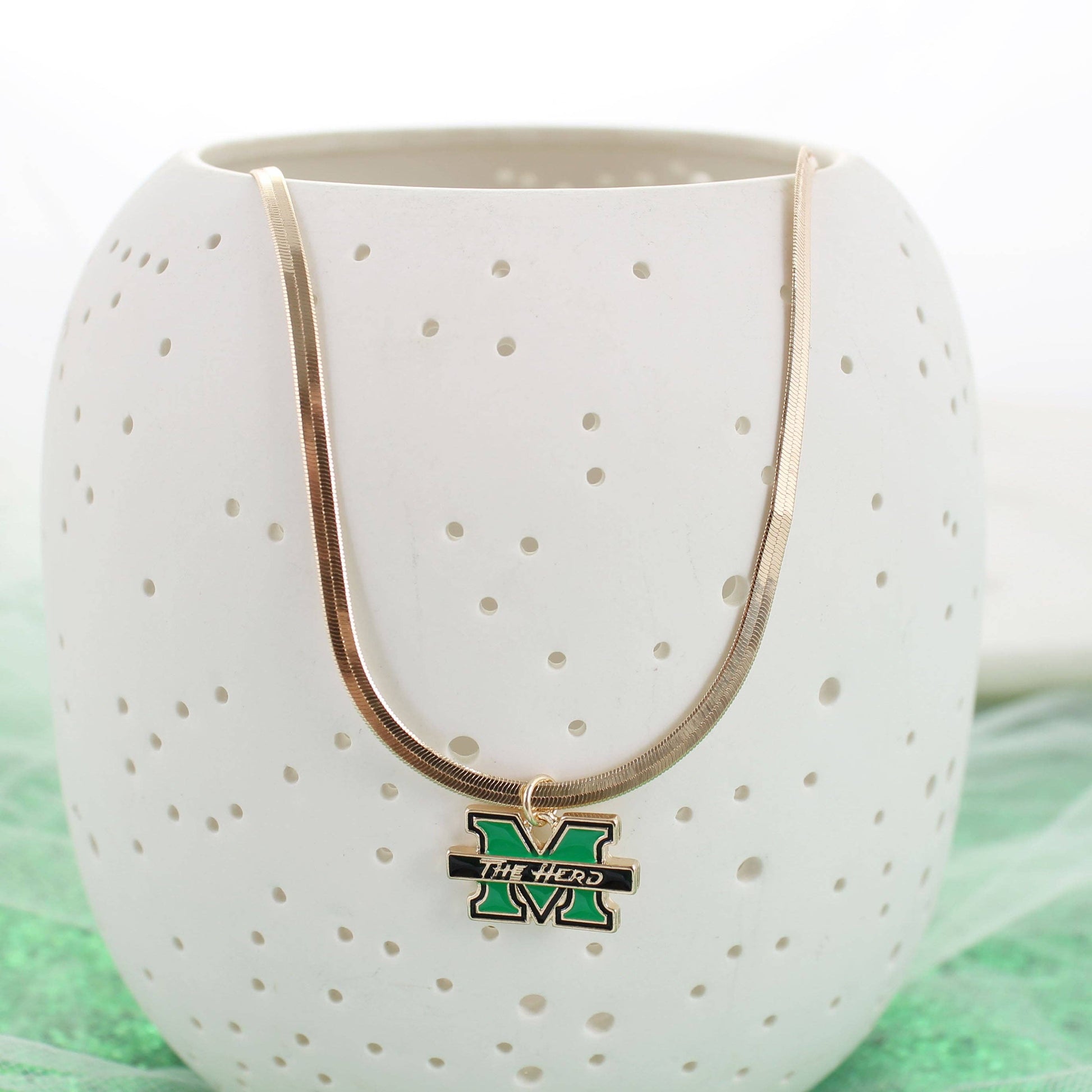Necklace with a pendant on a white vase against a green background