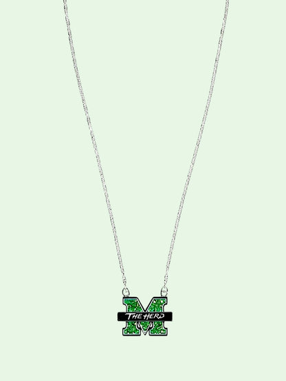 A silver chain necklace featuring a green and black enamel 'M' pendant with the text 'THE HERD' on a light mint green background.