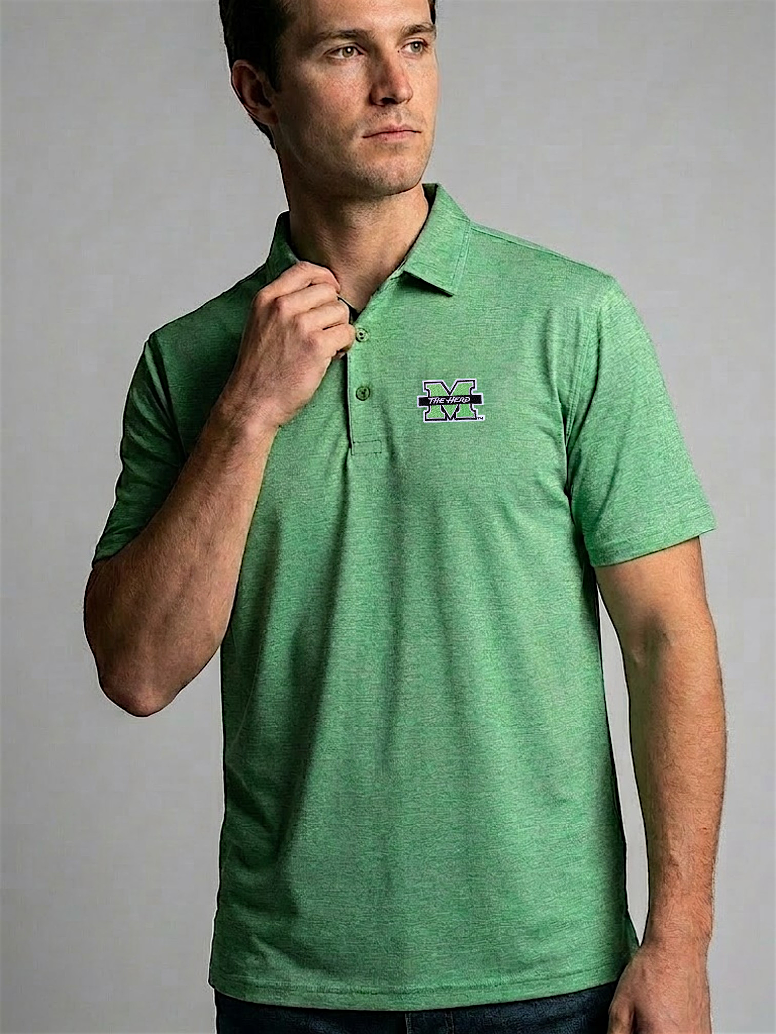 Man wearing a green polo shirt with a logo on a gray background