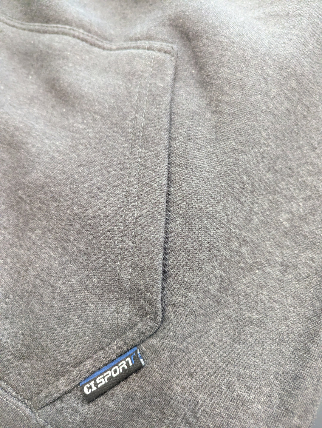 Gray fleece fabric with a visible brand label on a close-up of a pocket.