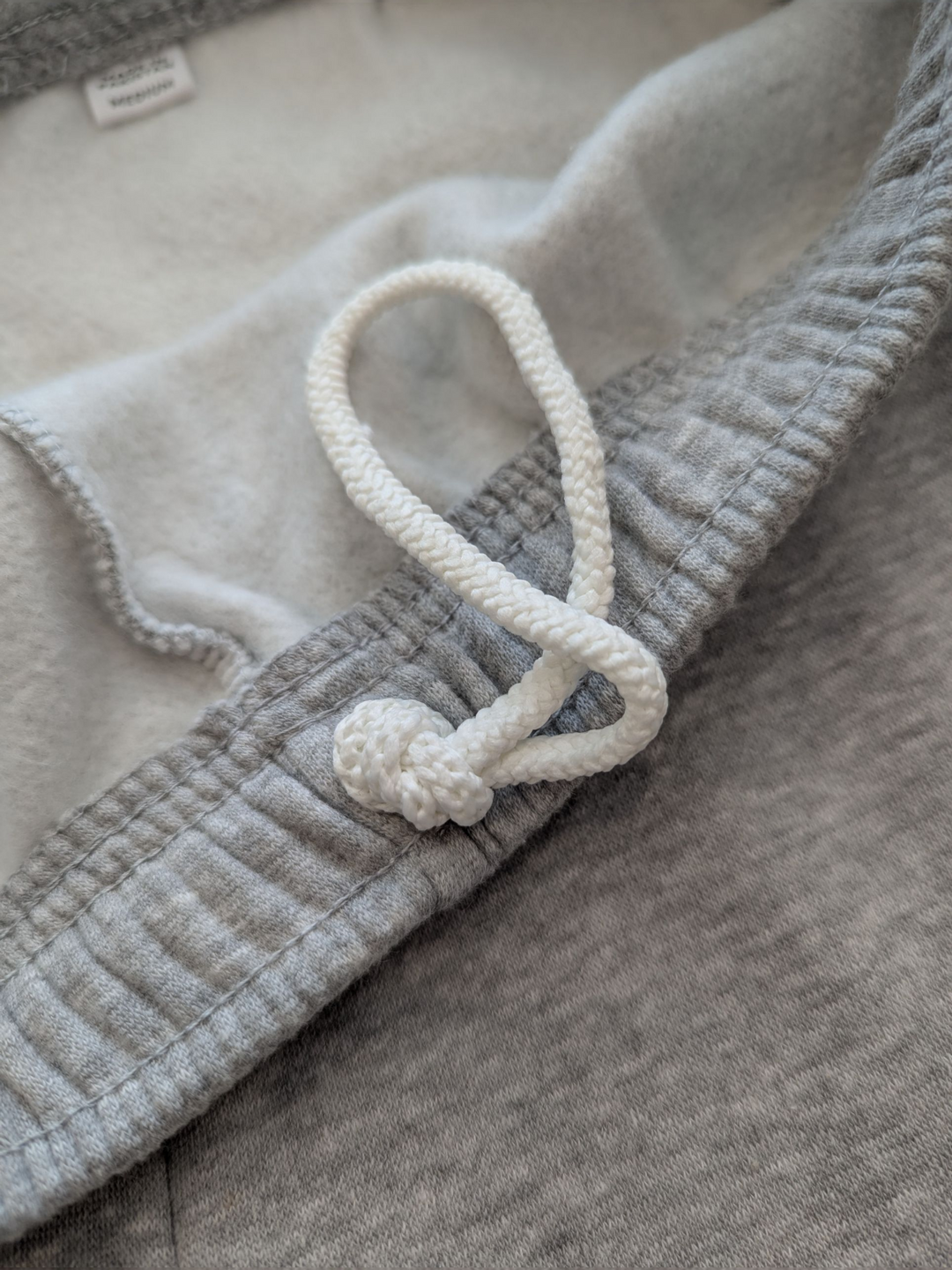 Close-up of a textured fabric with a white cord and knot detail.