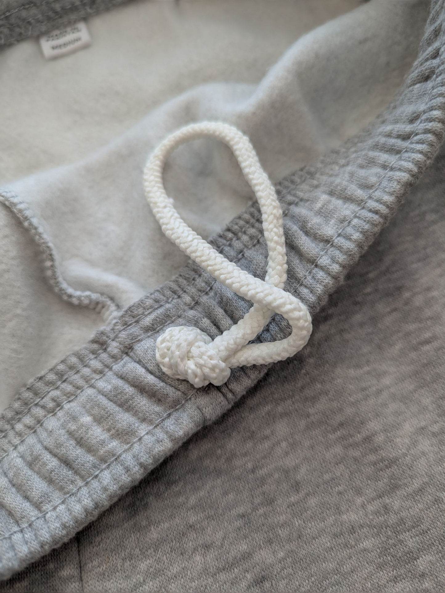 Close-up of a textured fabric with a white cord and knot detail.