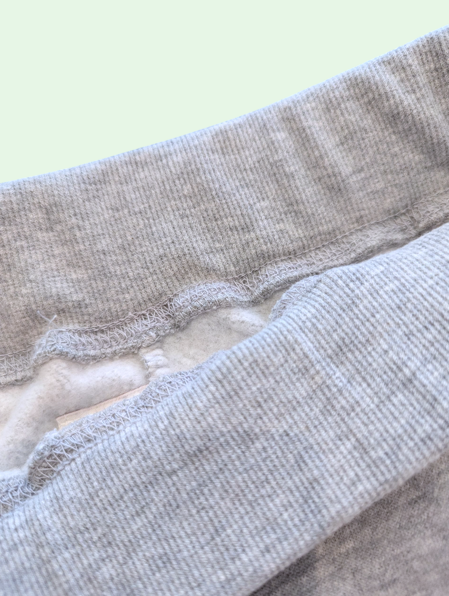 Close-up of gray fabric with a textured pattern on a light green background