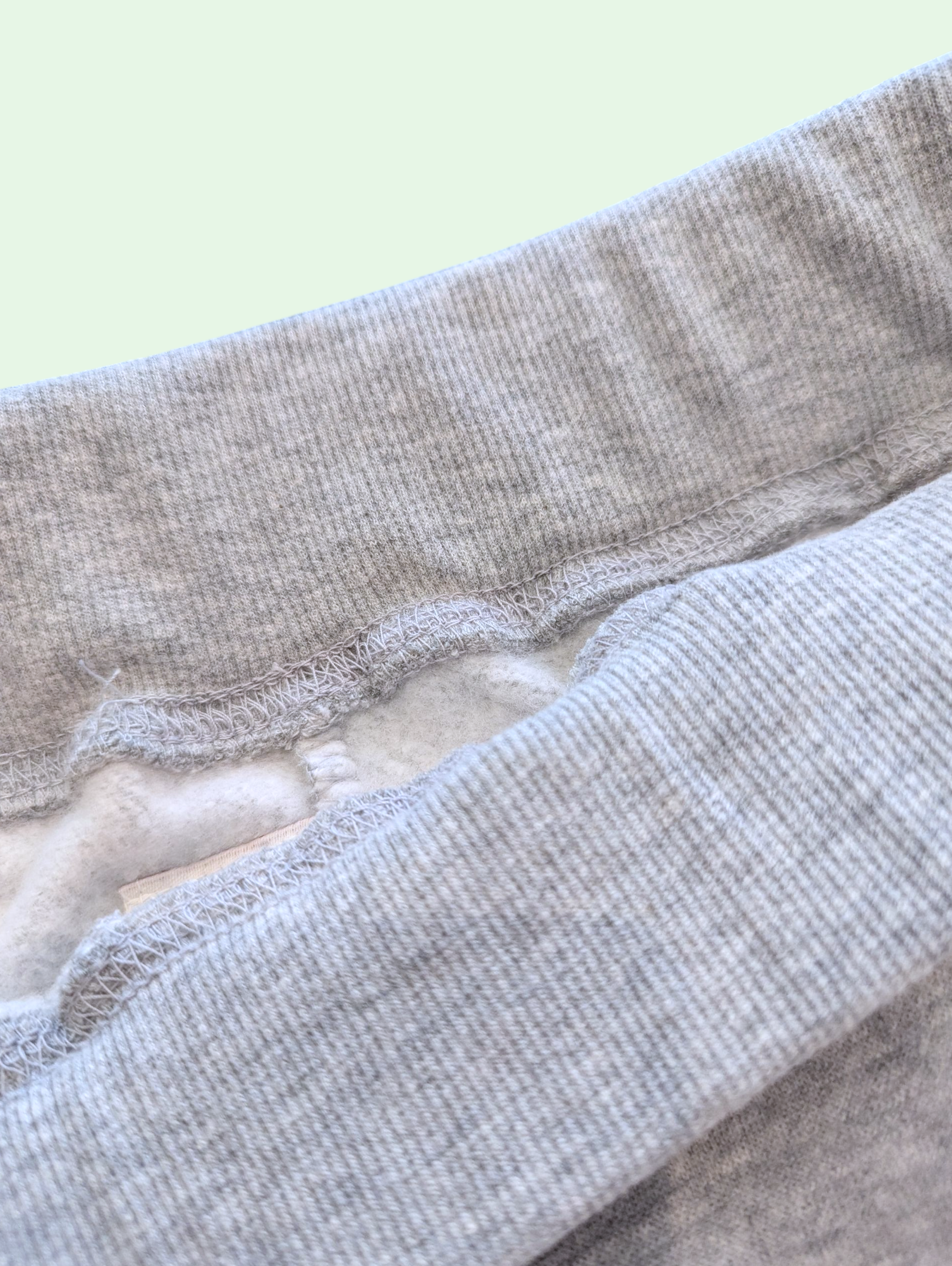 Close-up of gray fabric with a textured pattern on a light green background