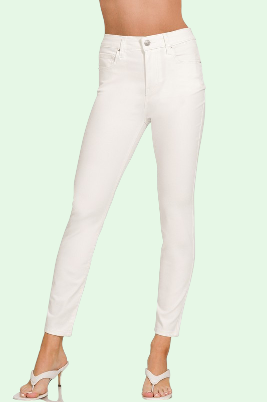 White jeans worn by a person on a light green background