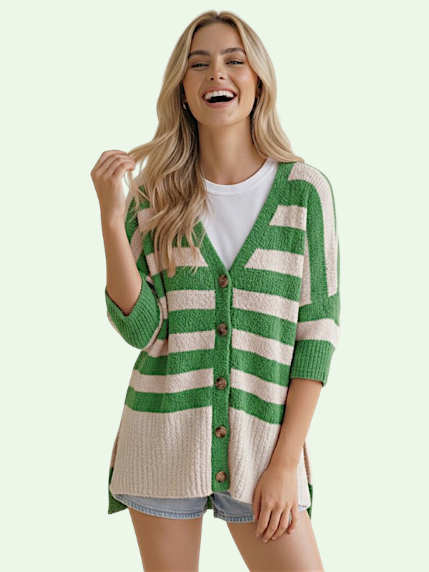 Woman wearing a green and white striped cardigan on a light background