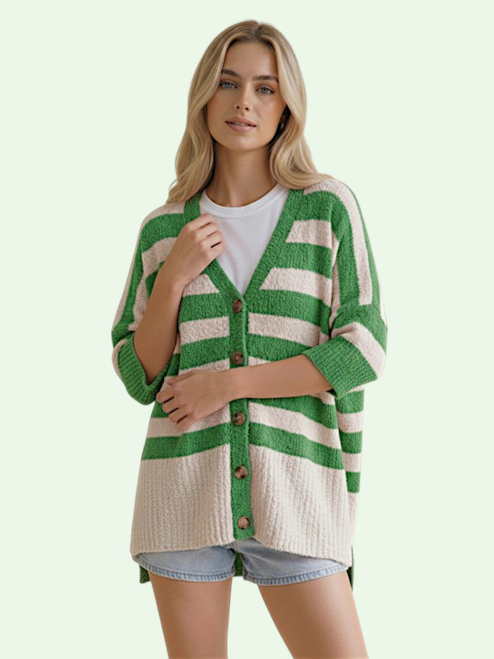 Woman wearing a green and beige striped cardigan on a light green background
