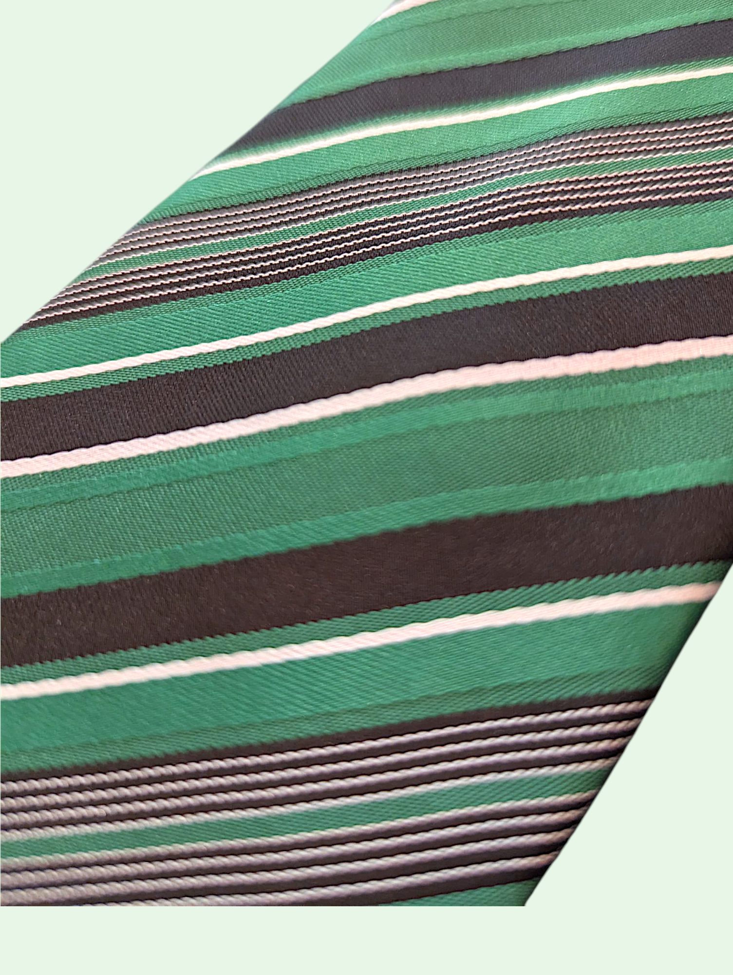 Close-up of a green striped tie with black and white stripes on a light green background