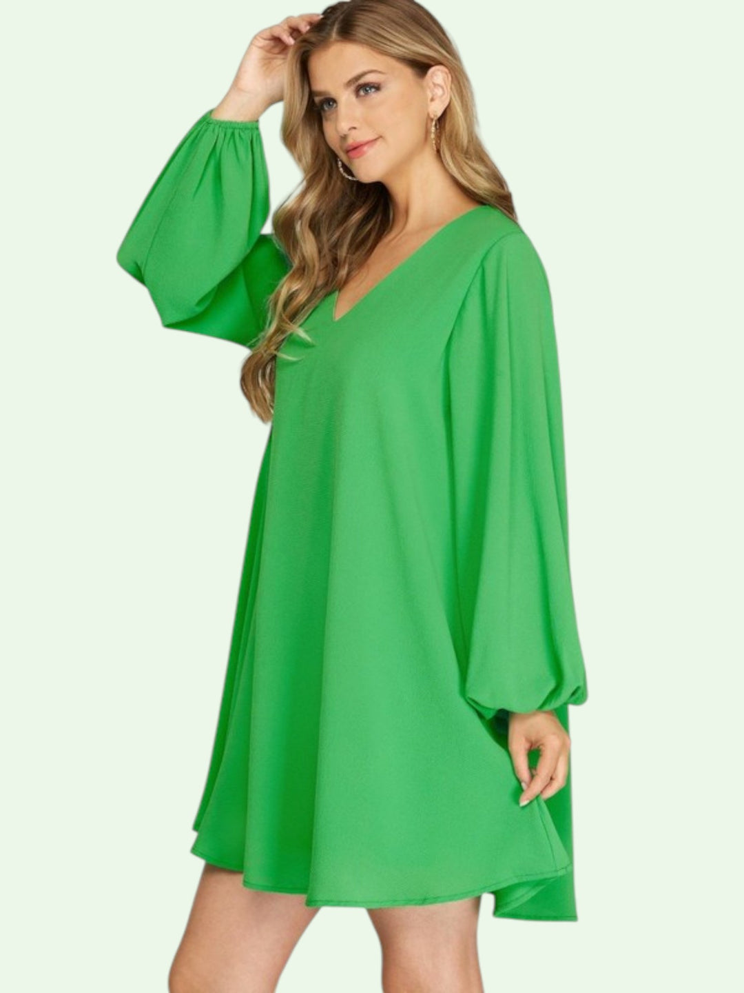 Woman wearing a green dress with wide sleeves on a white background