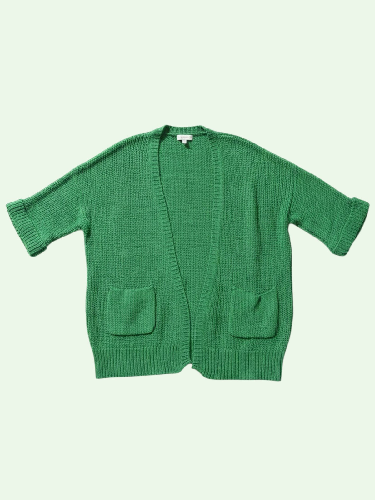 a green cardigan laid flat on a light green background