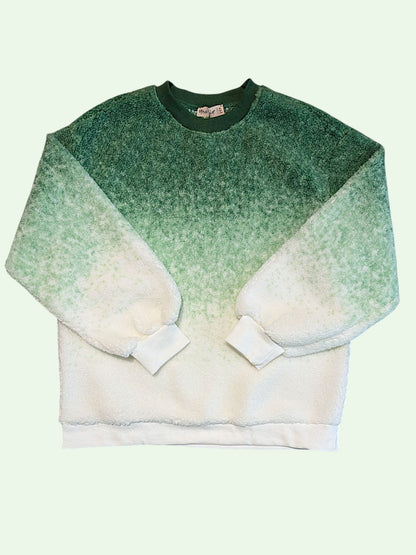A long-sleeve crewneck sweatshirt with a textured green-to-white ombre gradient, laid flat against a pale mint green background.