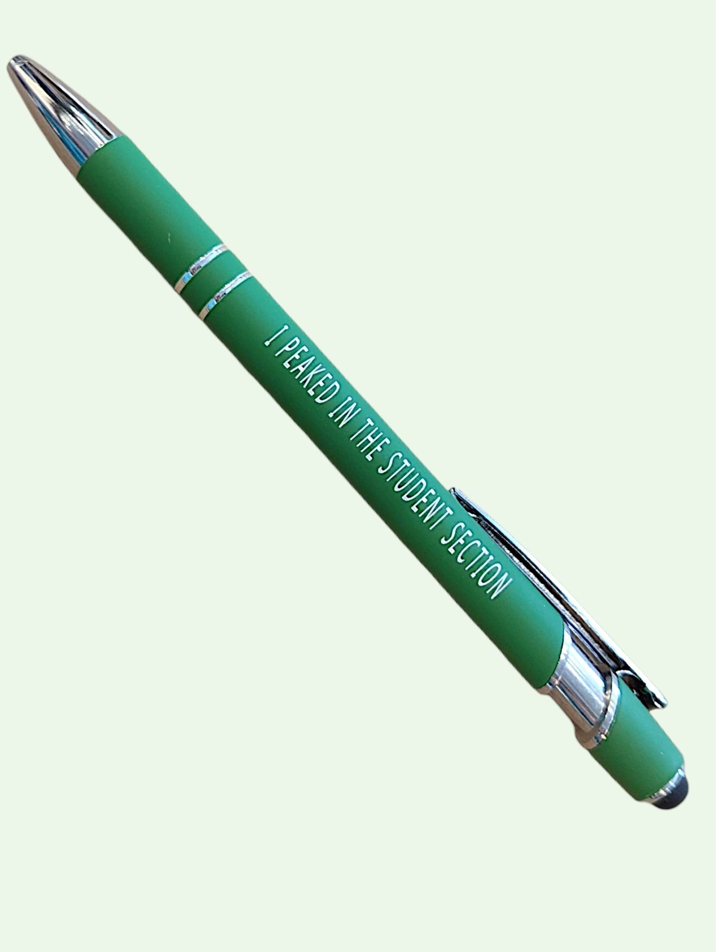 A green ballpoint pen with silver accents and white text that reads 'I PEAKED IN THE STUDENT SECTION', shown diagonally on a pale green background.