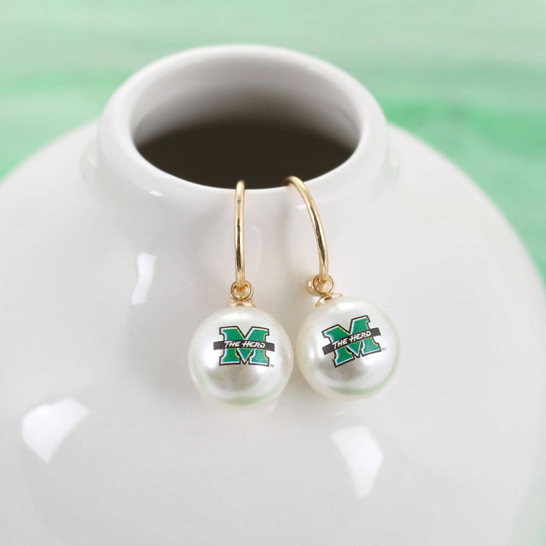 Pearl earrings with a logo on a white dish against a green background