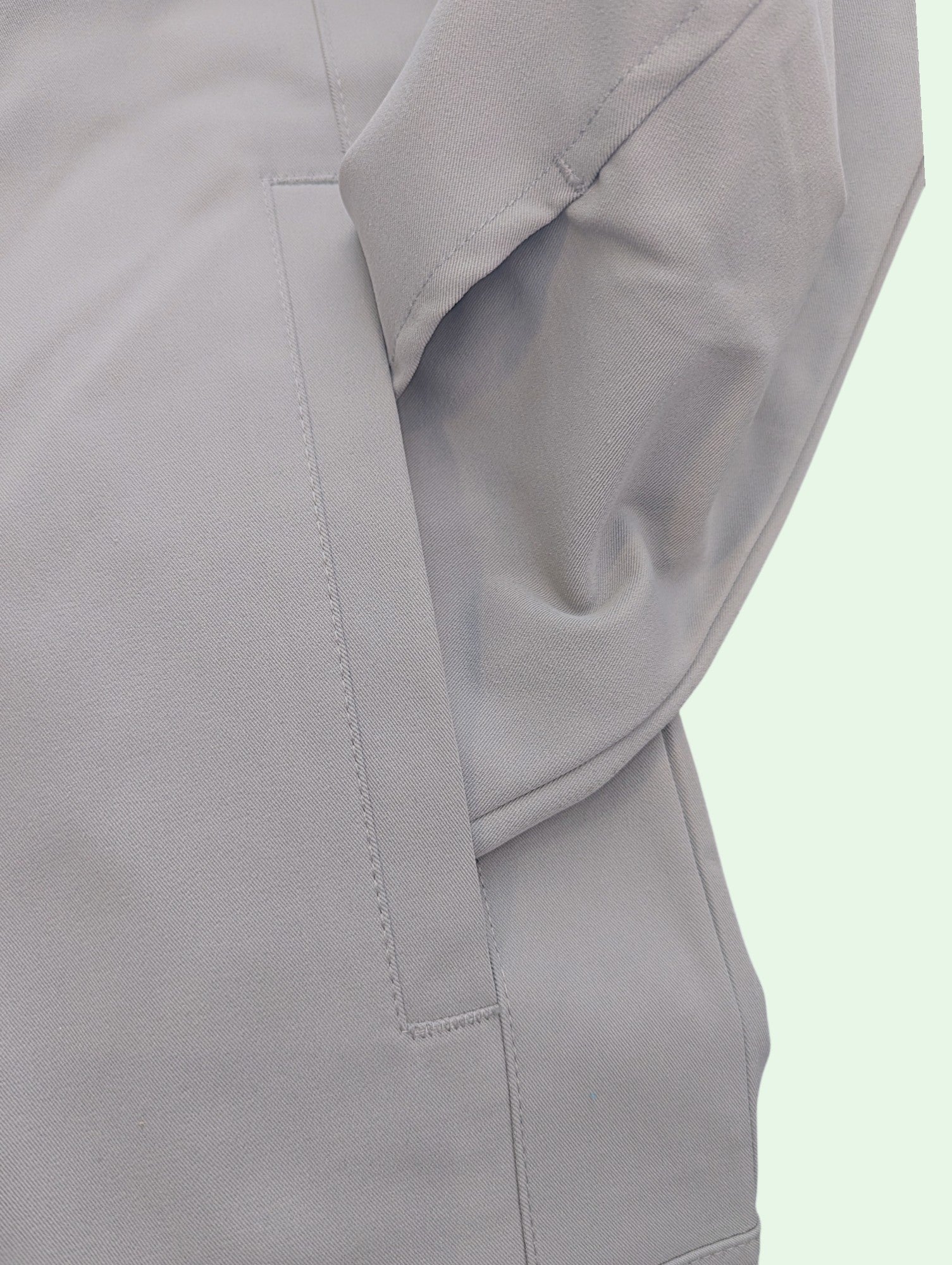 Close-up of a gray jacket slash pocket on a light green background