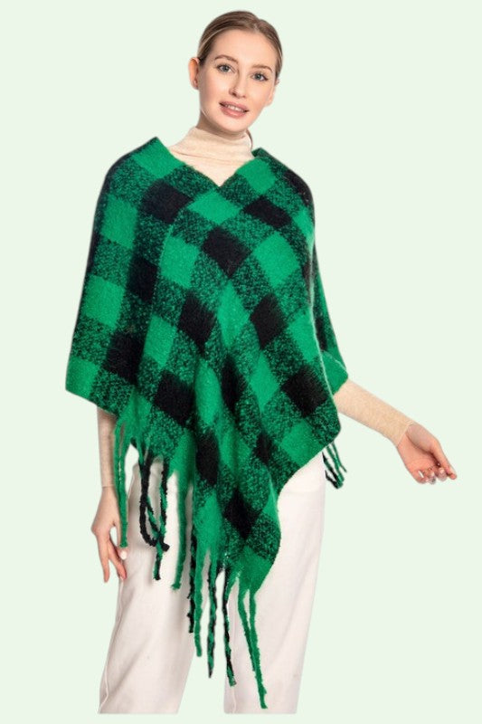 Woman wearing a green and black checkered poncho with tassels on a light green background