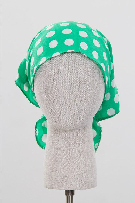 a green and white polka dot scarf tied into a kercheif on a manniquins head